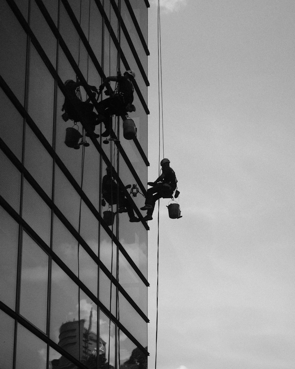 A black and white photo of a man on a window washer