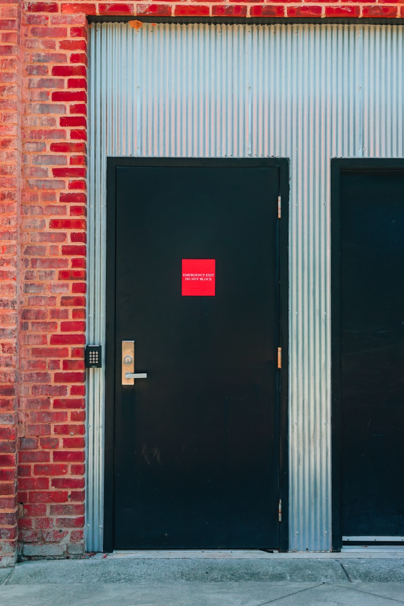 A black door is beside a brick wall.